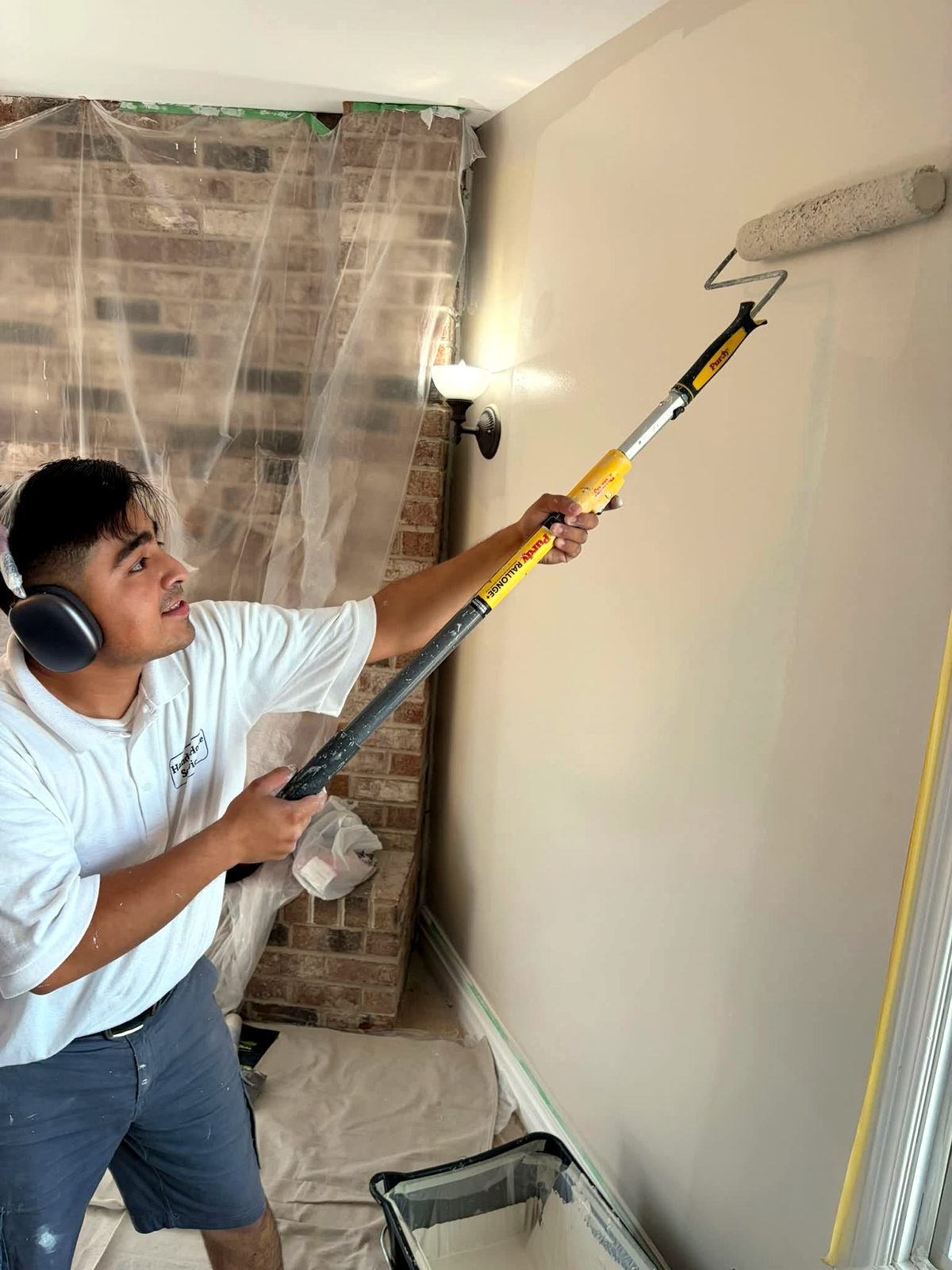 Handy Home painter rolling fresh paint on a living room wall