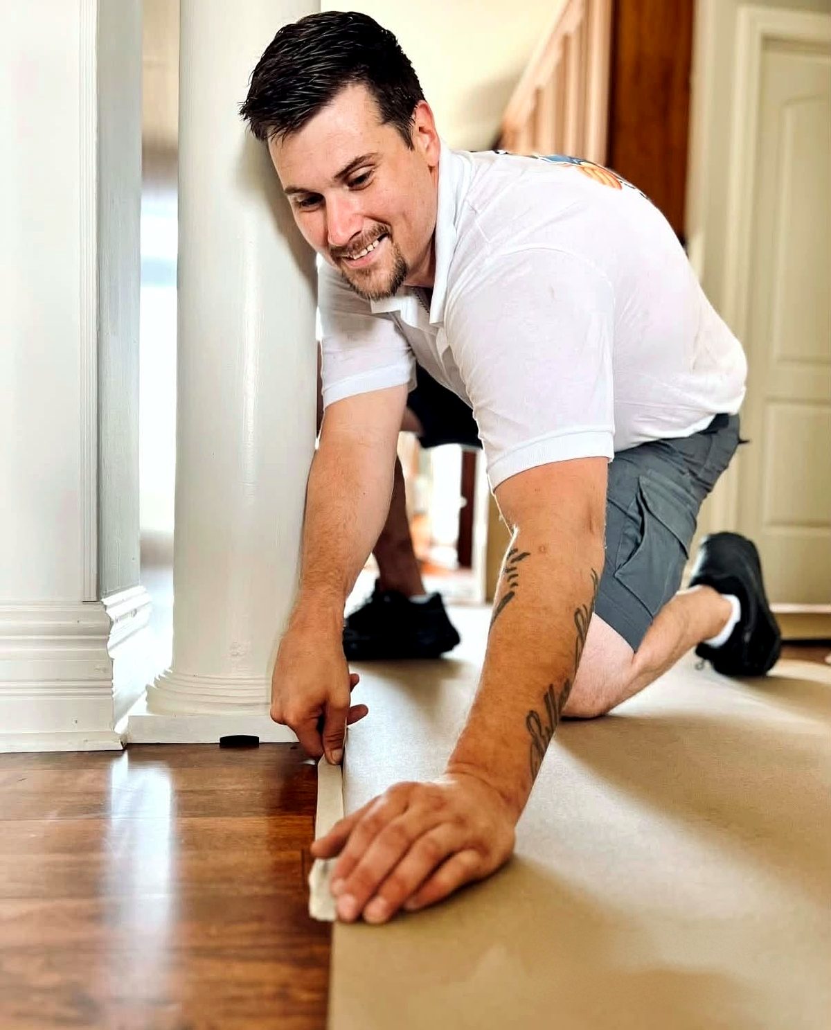 Handy Home crew member taping down floor protection next to a column before work starts